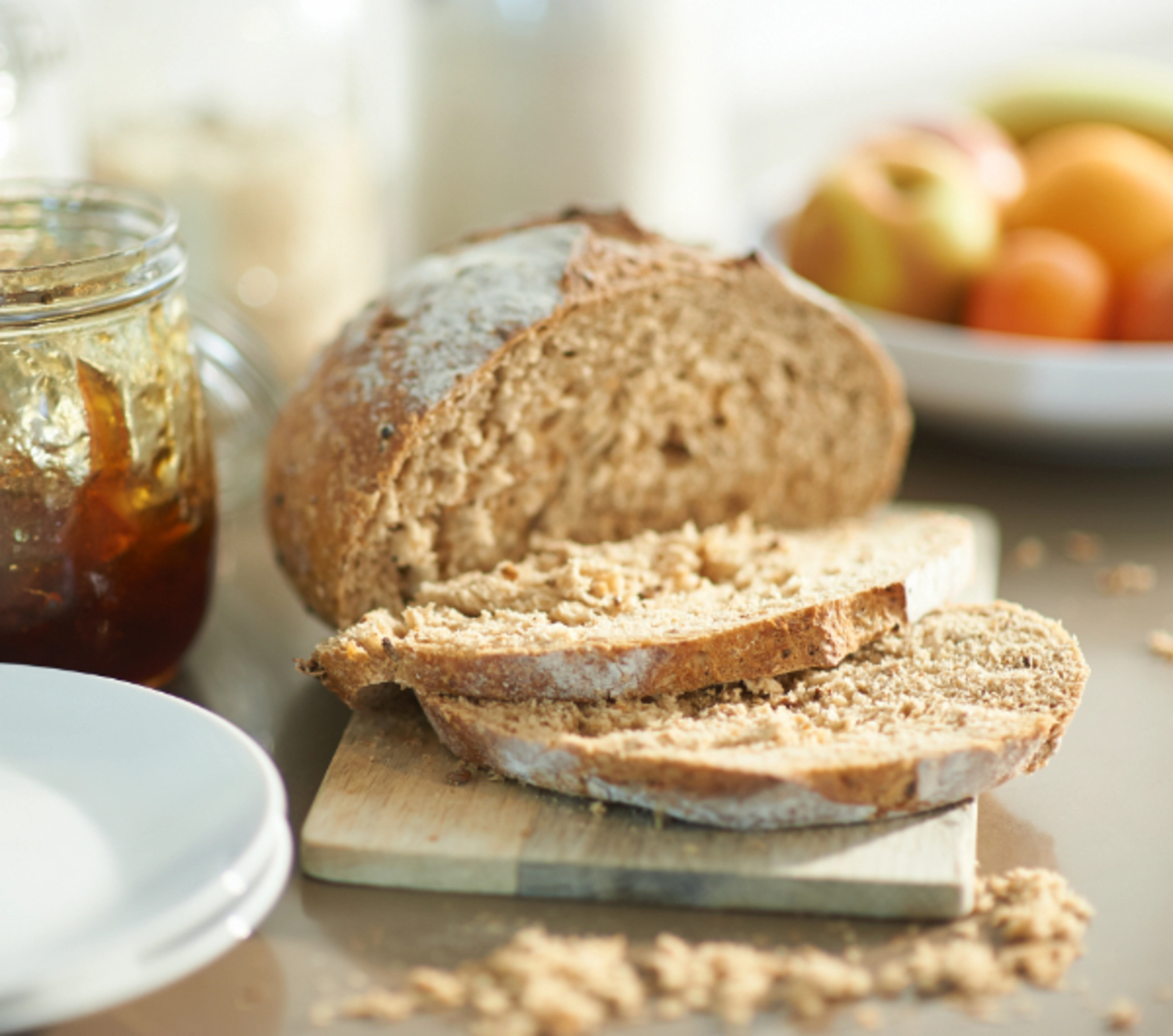 Sliced wheat bread next to a jar of jam.