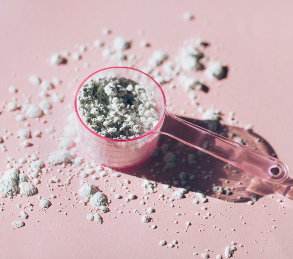A scoop of collagen powder on a pink background