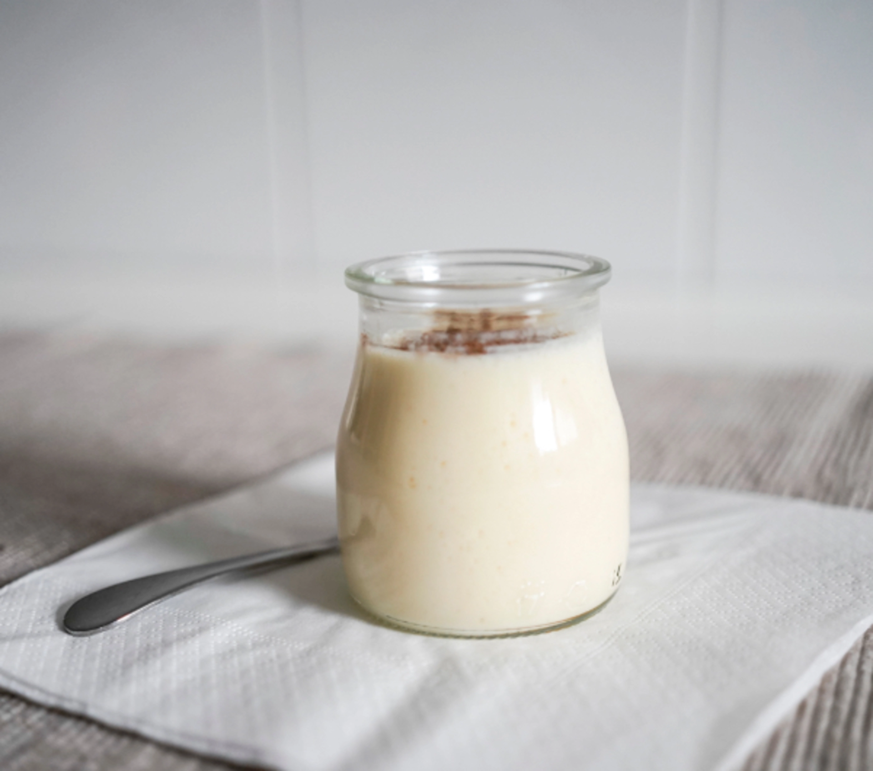 A bowl of yogurt with granola on top of a napkin.