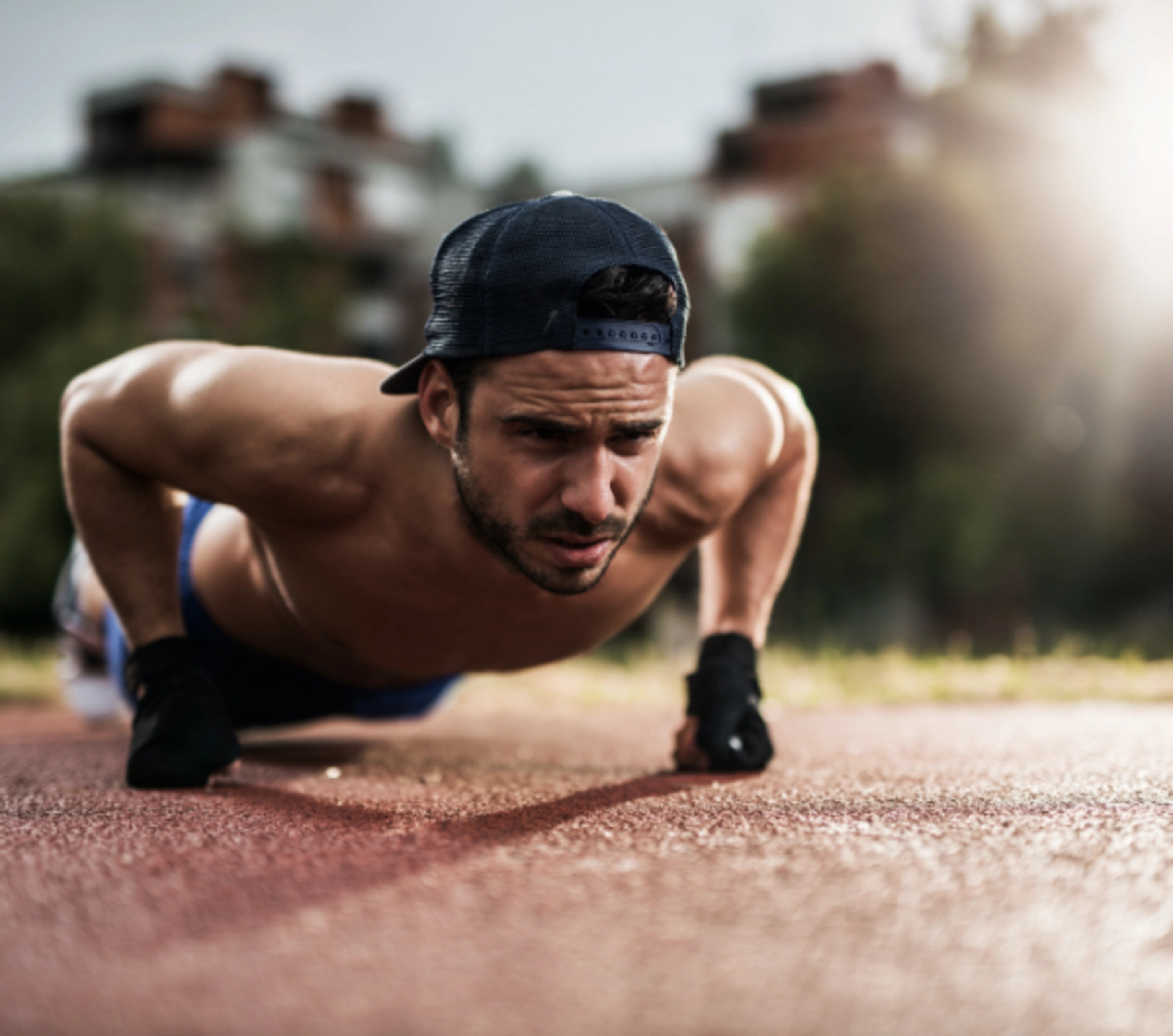 A man in a baseball hat doing push-ups.