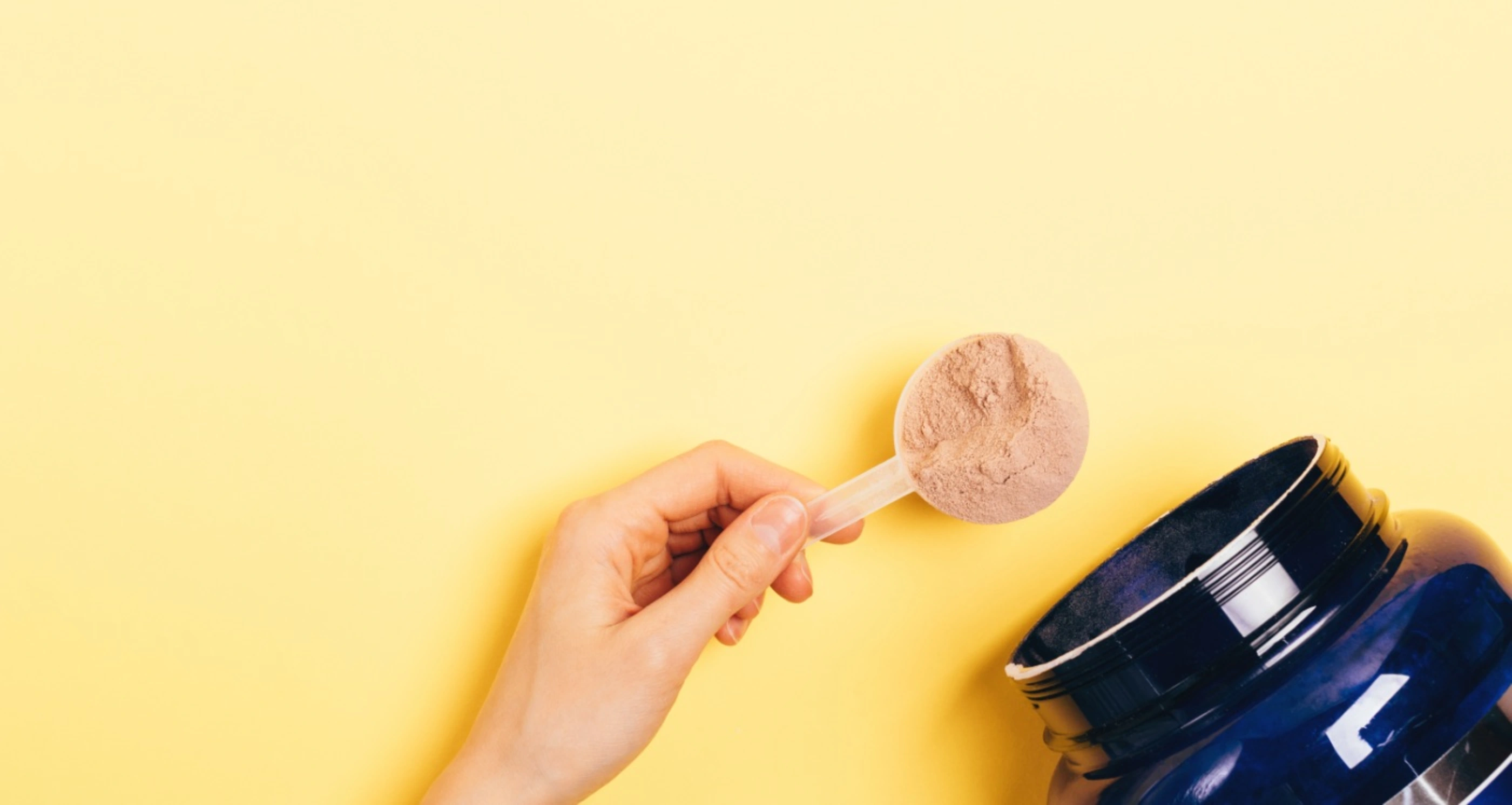 chocolate protein powder scoop on yellow background