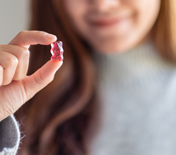 A woman holding a red gummy bear.