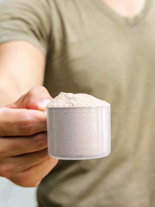 a person holding a scoop of brown powder