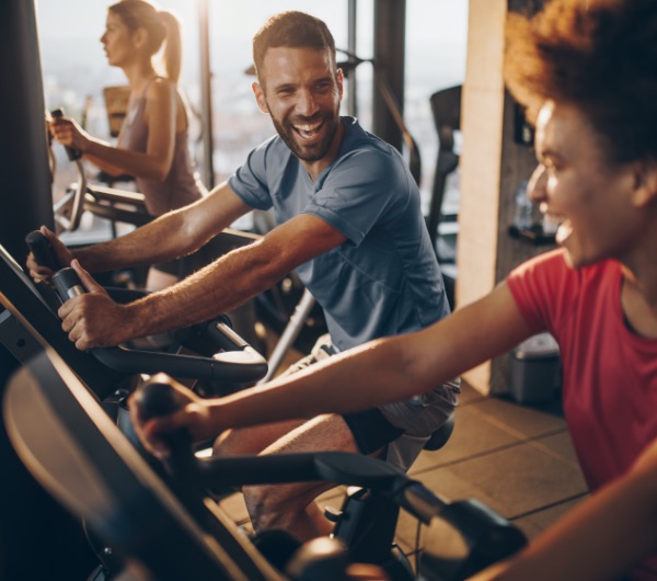 man and woman on stationary bikes in a gym