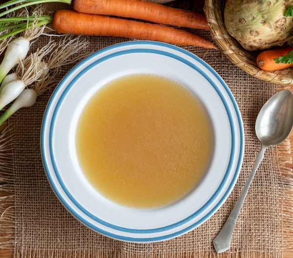 white bowl full of orange broth on a table