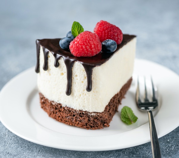 slice of cheesecake topped with berries on a white plate with a fork