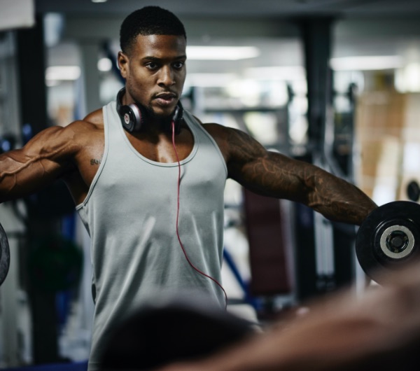 man lifting weights with headphones around his neck