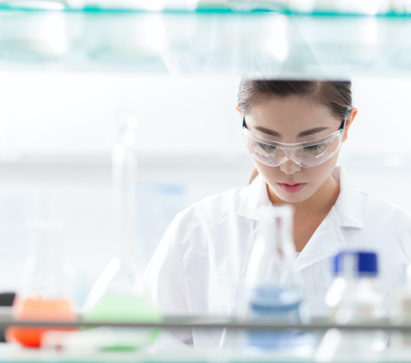 Scientist looking down at her work with test tubes filled with liquid in the foreground.