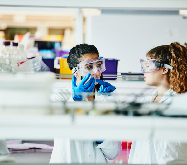 Two scientists looking at something inside of a test tube.
