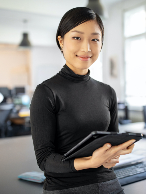 A woman in a black turtle neck smiling as she holds a tablet.