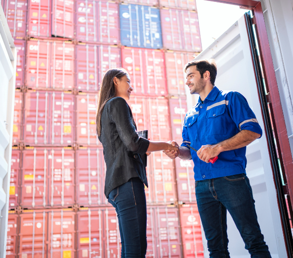 A woman holding a tablet shaking the hand of a man holding a handheld radio.