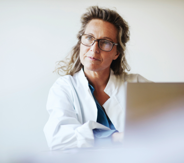 woman with glasses gazing up from laptop