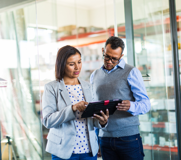 man and woman look at tablet in a warehouse