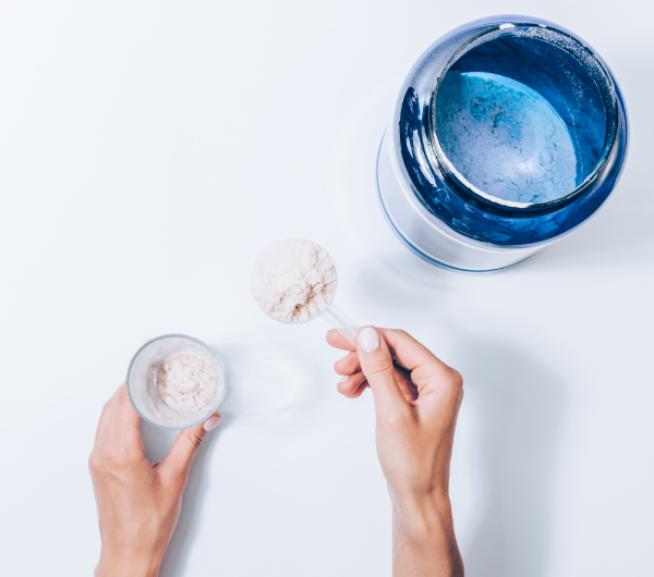 hands scooping powder from blue jar into glass