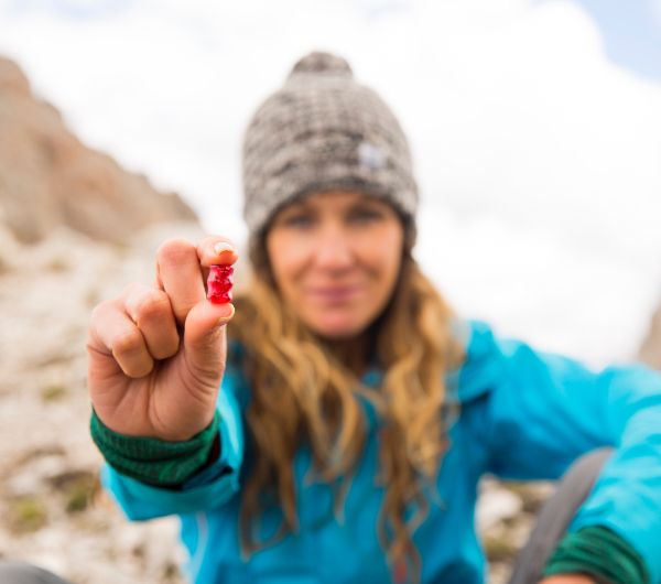 A woman holding a red gummy bear in front of the camera.