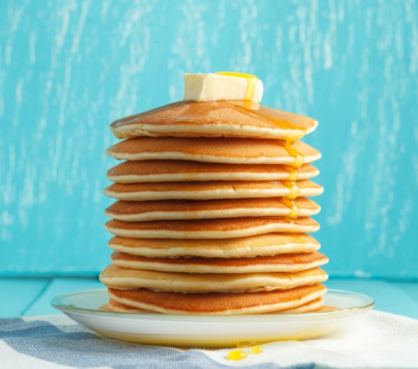 A stack of pancakes with butter and a maple flavor syrup
