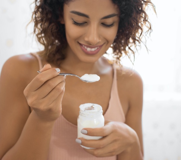 A young healthy woman smiling while eating yogurt