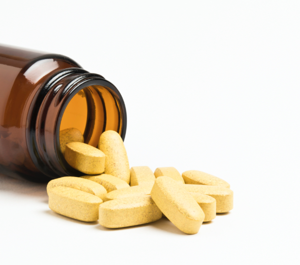 yellow pills spilling from brown bottle