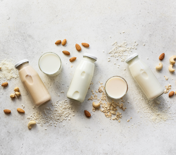 nut milks in glass bottles and dry good on concrete background