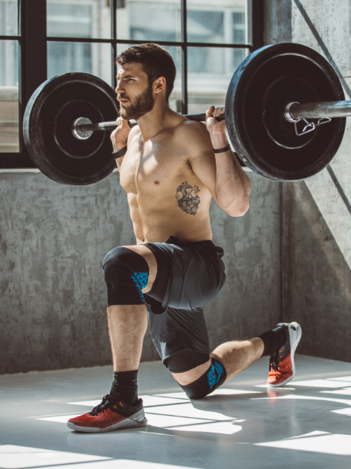 shirtless man lunging with weights