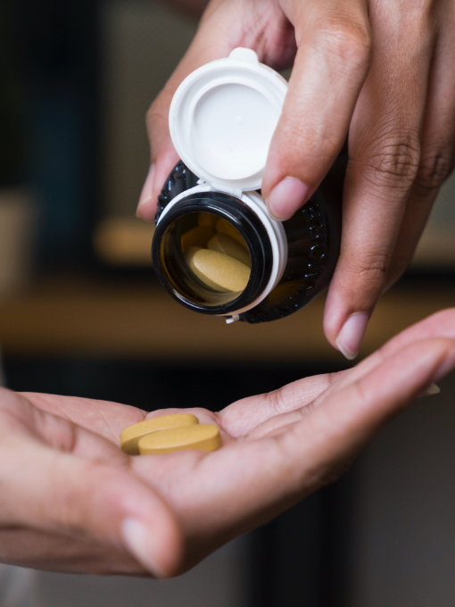 large brown pills falling from brown bottle into hand