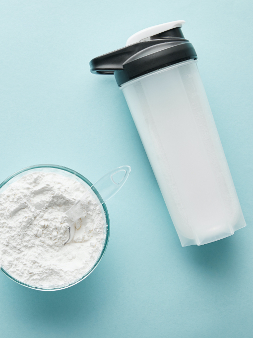 white powder in a glass next to a shaker bottle with black cap